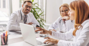 Medical billing software for small practices - A team of doctors using a laptop and discussing their use of medical billing software.