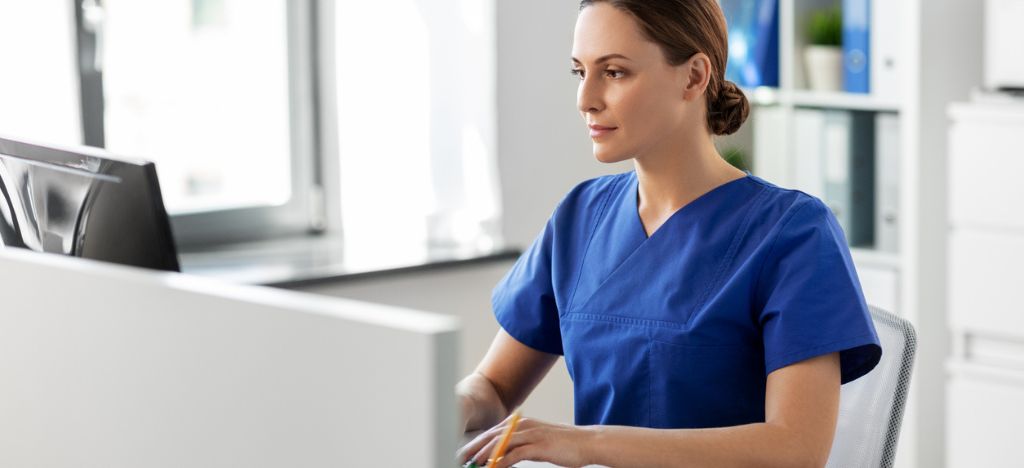 Female front desk medical office staff member working at desktop PC.