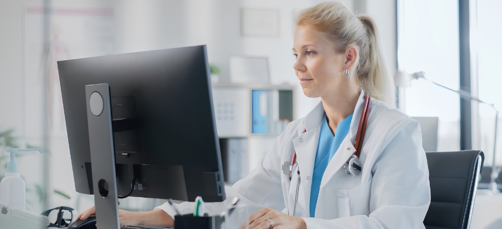 Medical professional using a desktop pc at their medical office desk.
