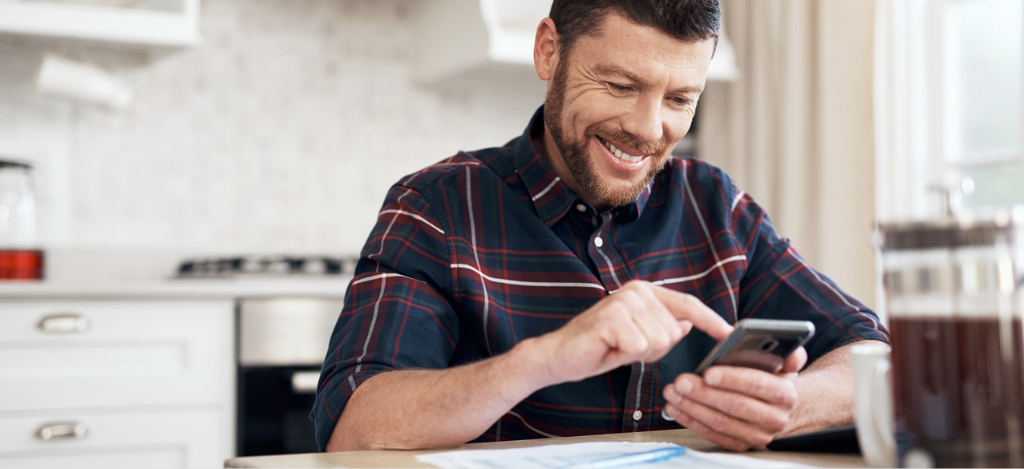 A man at home using his smartphone to access his medical bill.