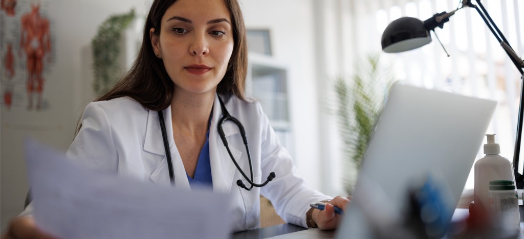 Using mailed and eBills - A female doctor reviewing a patient’s medical bill.