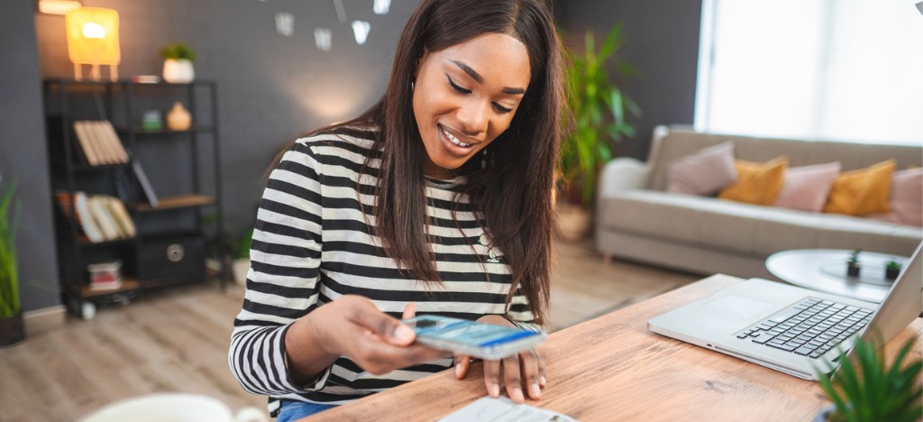 Healthcare revenue cycle strategies - A woman at home using her smartphone to scan a QR code printed on her medical bill.