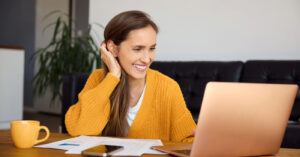 Payment options - A woman at home using her smartphone and laptop to pay for her hospital bills.