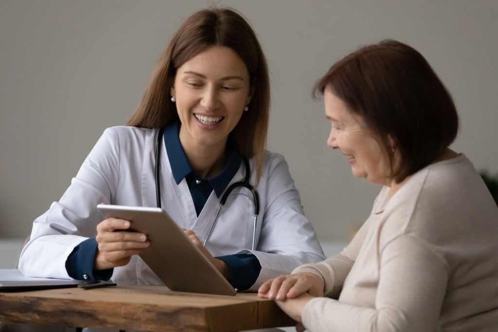 Healthcare technology for patient payments - A female doctor using a tablet device while explaining payment options to her senior patient.