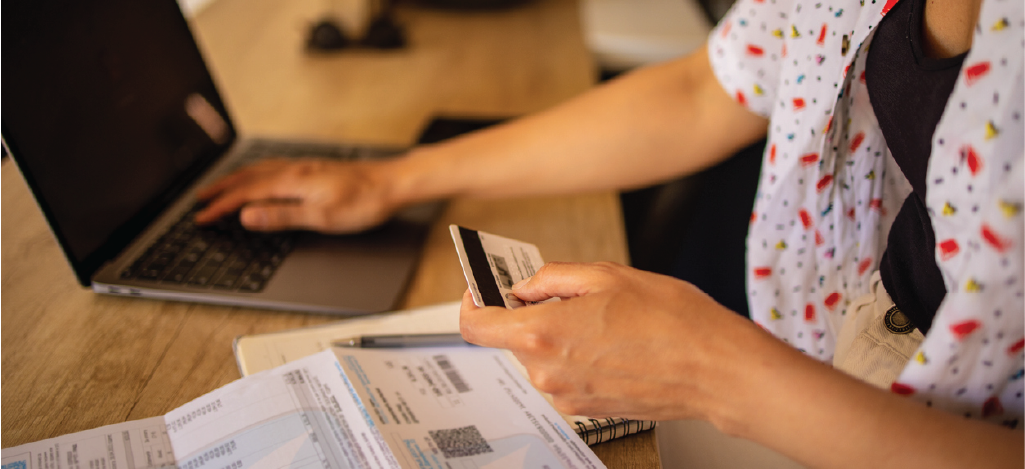 Mental health billing software options - A woman at home paying her medical bill using her credit card and laptop.