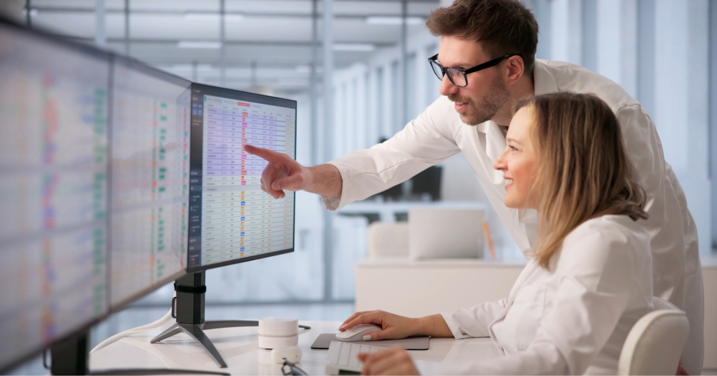Healthcare RCM companies - Two medical professionals looking at several computer monitors to check for their practice’s billing and collections software.