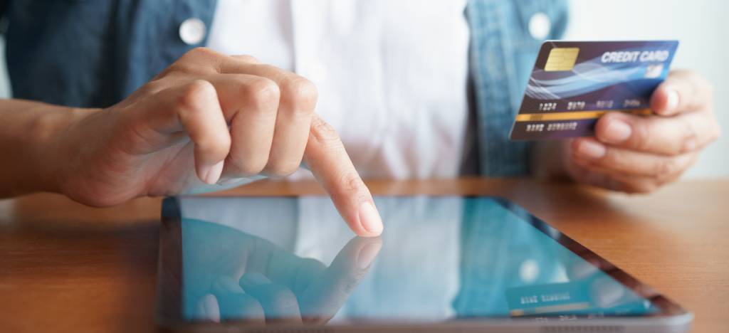 Payment Processing Ecosystem: Cropped shot of person tapping on a smart tablet while holding their credit card.