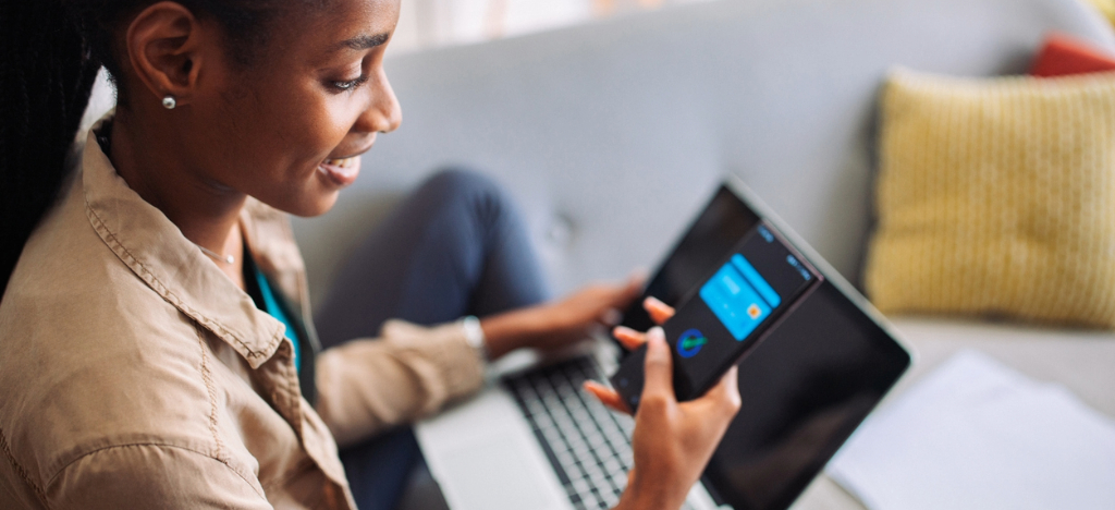 Patient messaging - A woman at home paying her medical bills online using her smartphone and laptop.