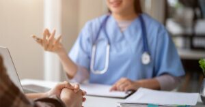 Improving patient financial experience - A female doctor talking to her patient during a consultation.