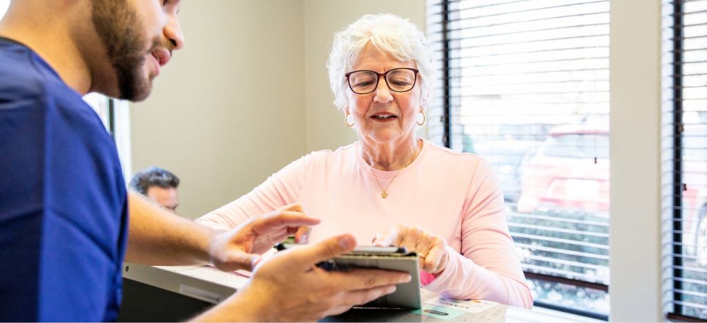 Patient payment plan - A male hospital staff member using a tablet device to help a female senior patient pay for her medical bills.