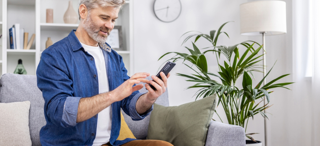 Automatic payment programs - A mature man at home using a smartphone to pay for his medical bills.