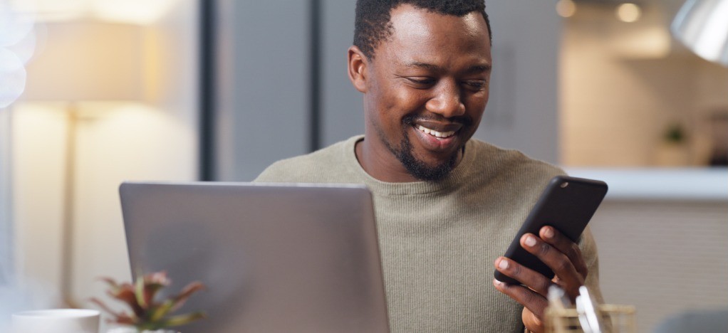 Healthcare revenue cycle strategies - A man reviewing his medical bill using a smartphone and laptop.