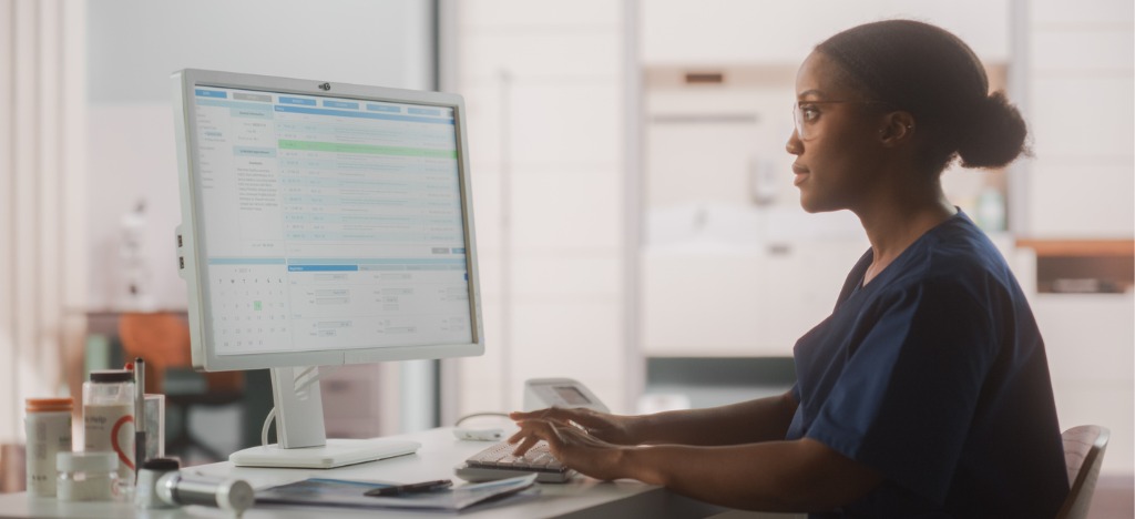 Automated payment reminders for practices - A female medical staff member using a computer to review patient bills.