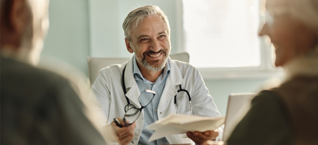 Adapting to the modern healthcare landscape - A male doctor talking to his senior patients during their medical appointment.