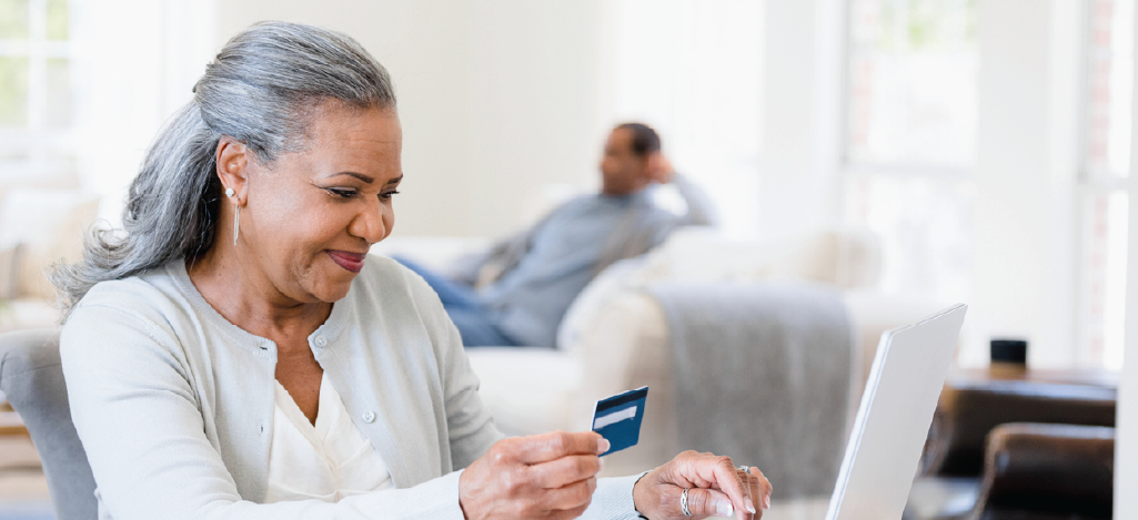 Medical billing solutions for faster patient response - A senior woman at home holding a credit card while paying her medical bill online.