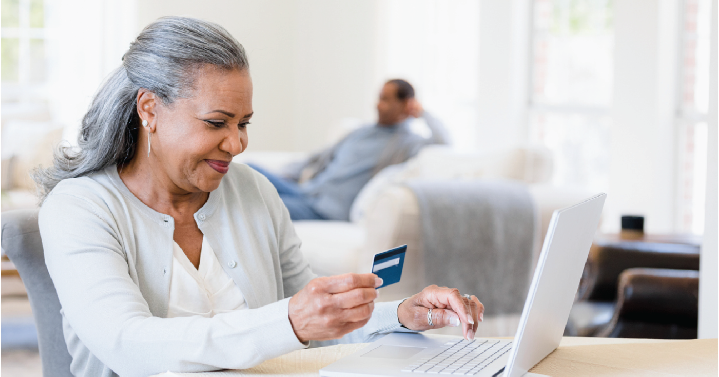 Medical billing solutions for faster patient response - A senior woman at home holding a credit card while paying her medical bill online.