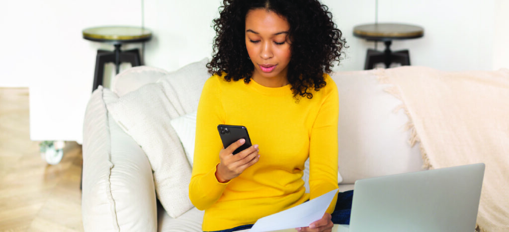 Sending automated reminders - A woman at home checking an automated billing notification on her phone.