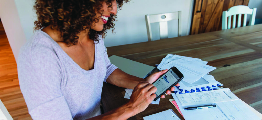 Pre-visit billing for patients - A woman at home using her smartphone to check her medical bill online.