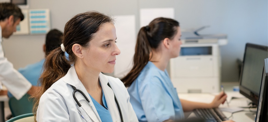 Automation in healthcare - A female doctor working with other healthcare professionals at a hospital’s billing desk.