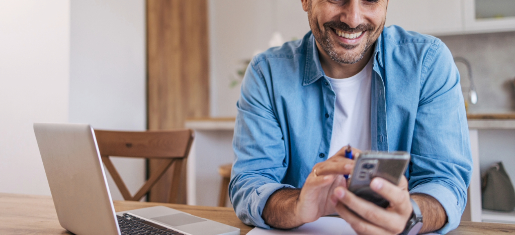 Reducing patient cancellations - A man at home using a smartphone to check for his medical bill notifications.