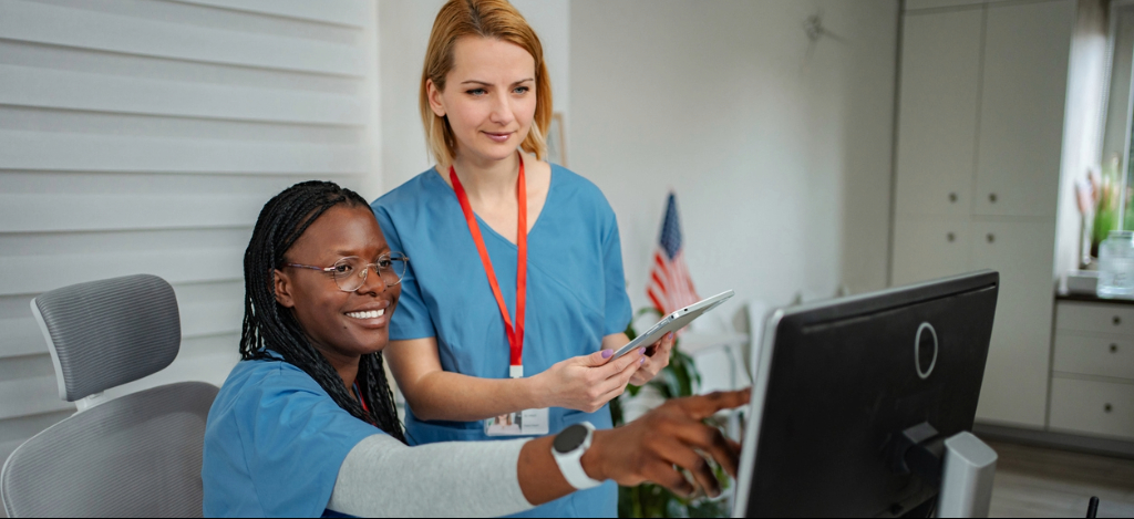 Healthcare billing staff reviewing patient account information together on one computer screen in a medical office.
