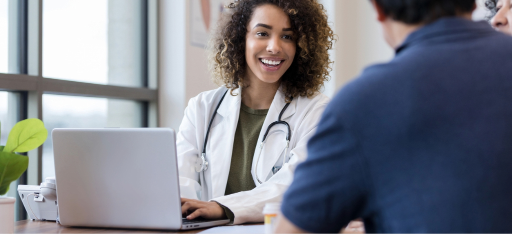 A female doctor using a laptop while talking to her patients during a medical appointment.