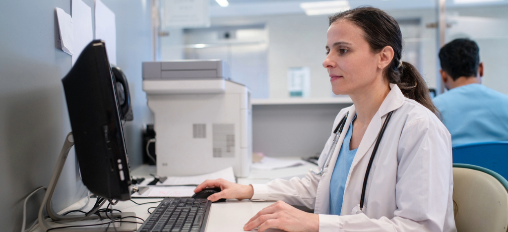 Healthcare RCM companies - A female doctor using a computer to access her practice’s billing software.