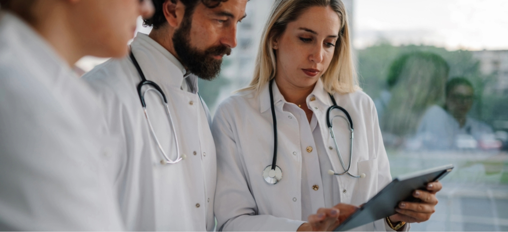 Patient payment solutions - Three doctors using a tablet device to check their practice’s billing solutions.