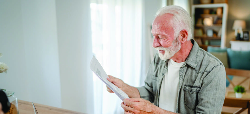 Diverse methods to pay - A senior man at home reviewing his medical bill.