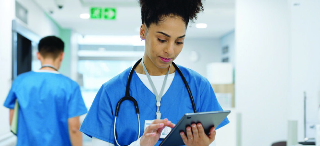 Reducing healthcare burnout - A female healthcare worker using a tablet device to check patient information.