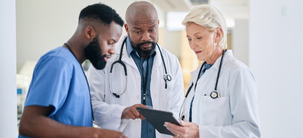 Using automated payment reminders - A group of healthcare professionals looking at patient bills on a tablet device.